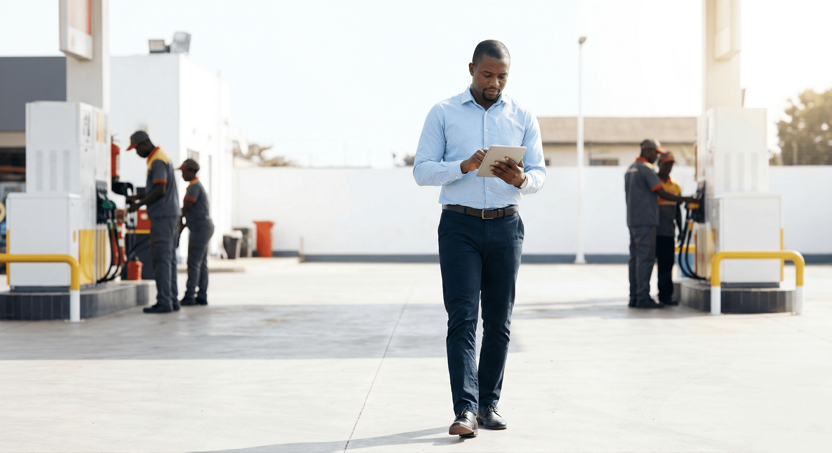 Responsable utilisant une tablette entre les pompes à carburant